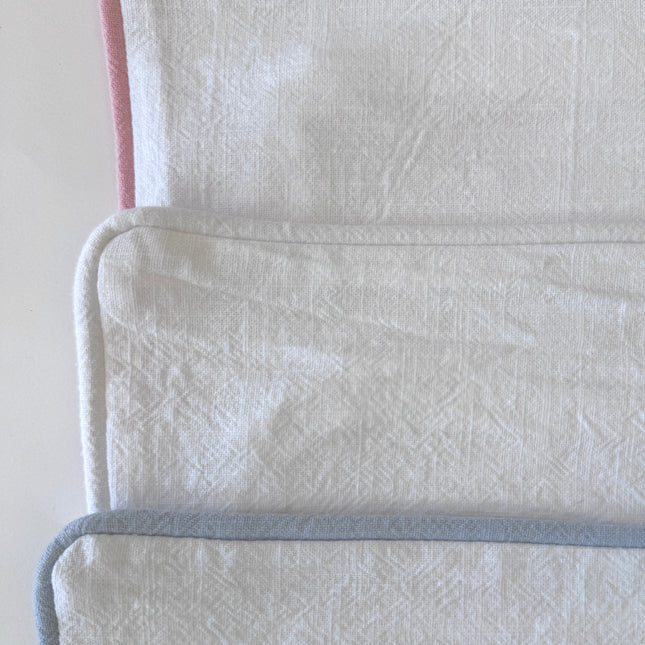 Three pillow covers with a pink, blue and white borders on a white background