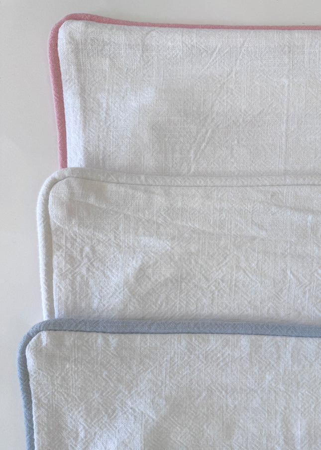 Three pillow covers with a pink, blue and white borders on a white background