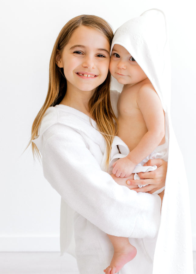Two children wrapped in white towels on a white background
