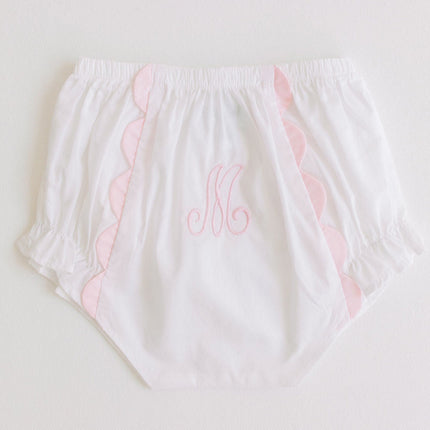 White diaper cover with pink scalloped edges and a monogram on a light background