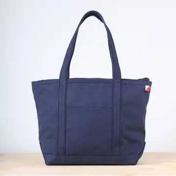 Navy blue tote bag on a light wooden surface with a white background