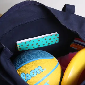 Navy blue backpack with a yellow basketball and teal polka dot item inside