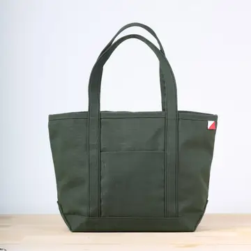Green tote bag on a light wooden surface with a white background